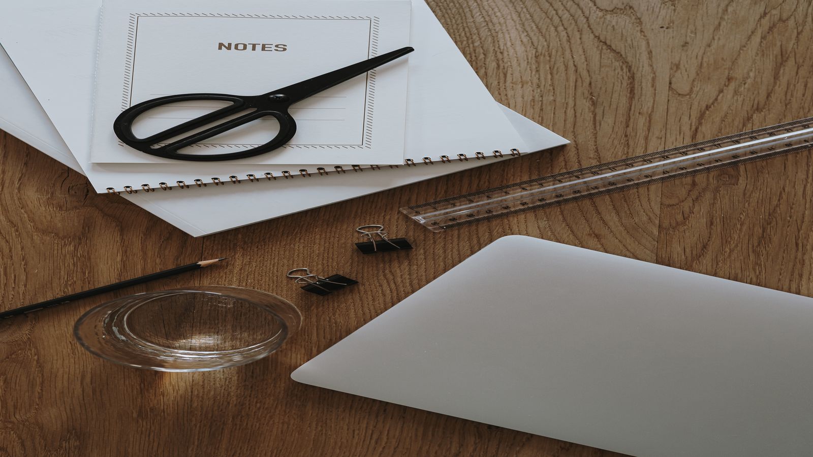 A desk covered in press clippings and trend charts with a magnifying glass resting on a calm notebook